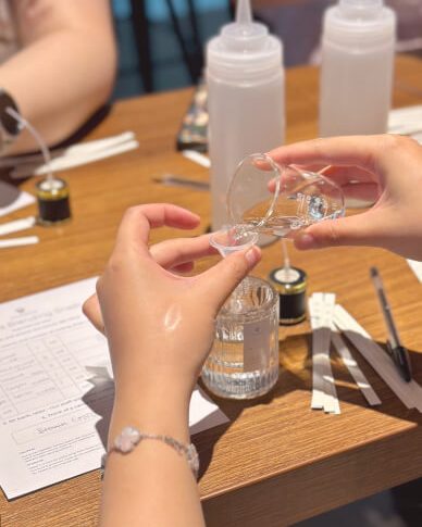 Hands pouring liquid lip gloss into tubes in the Glorious studio